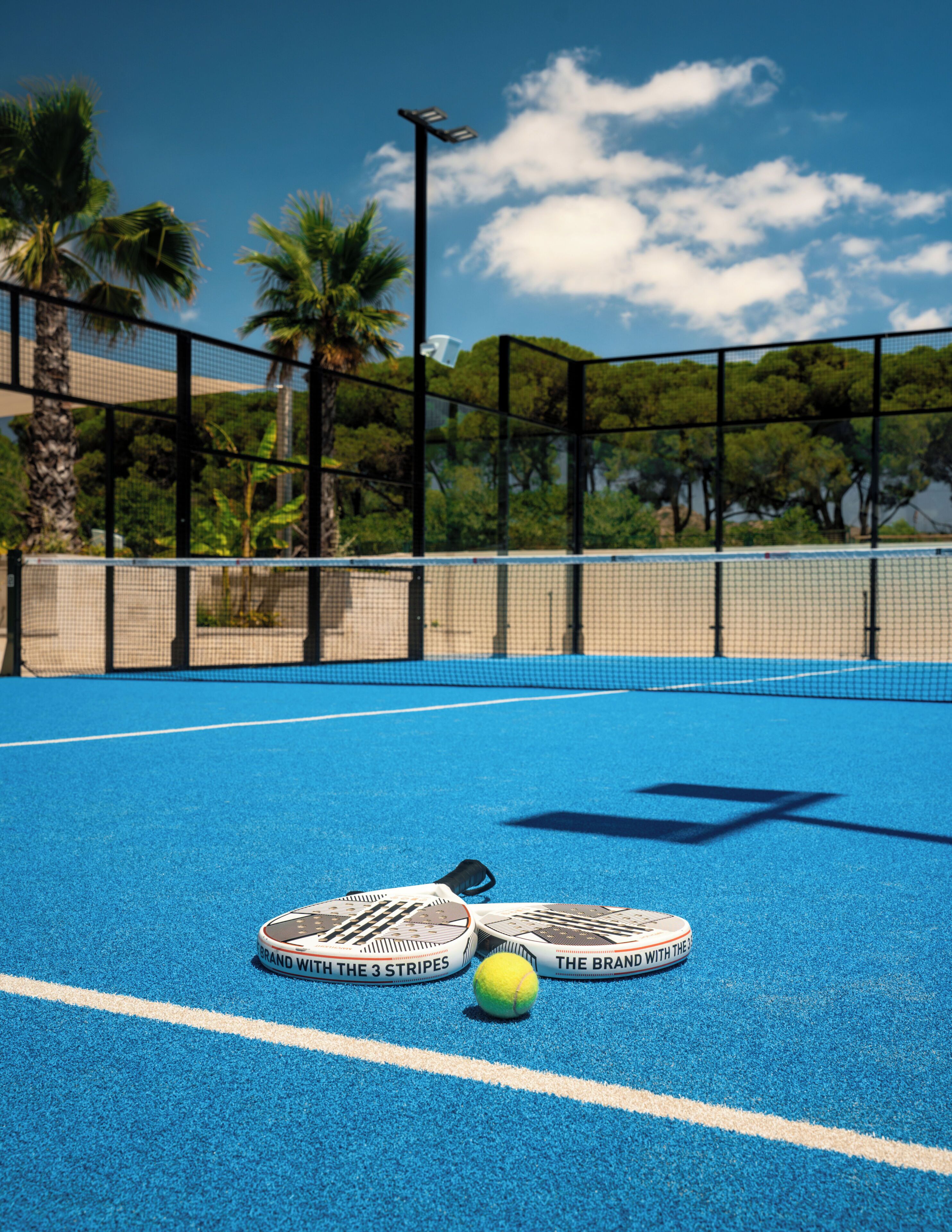 Ein Tennisplatz mit Netz, zwei Tennisschlägern und einem Tennisball.
