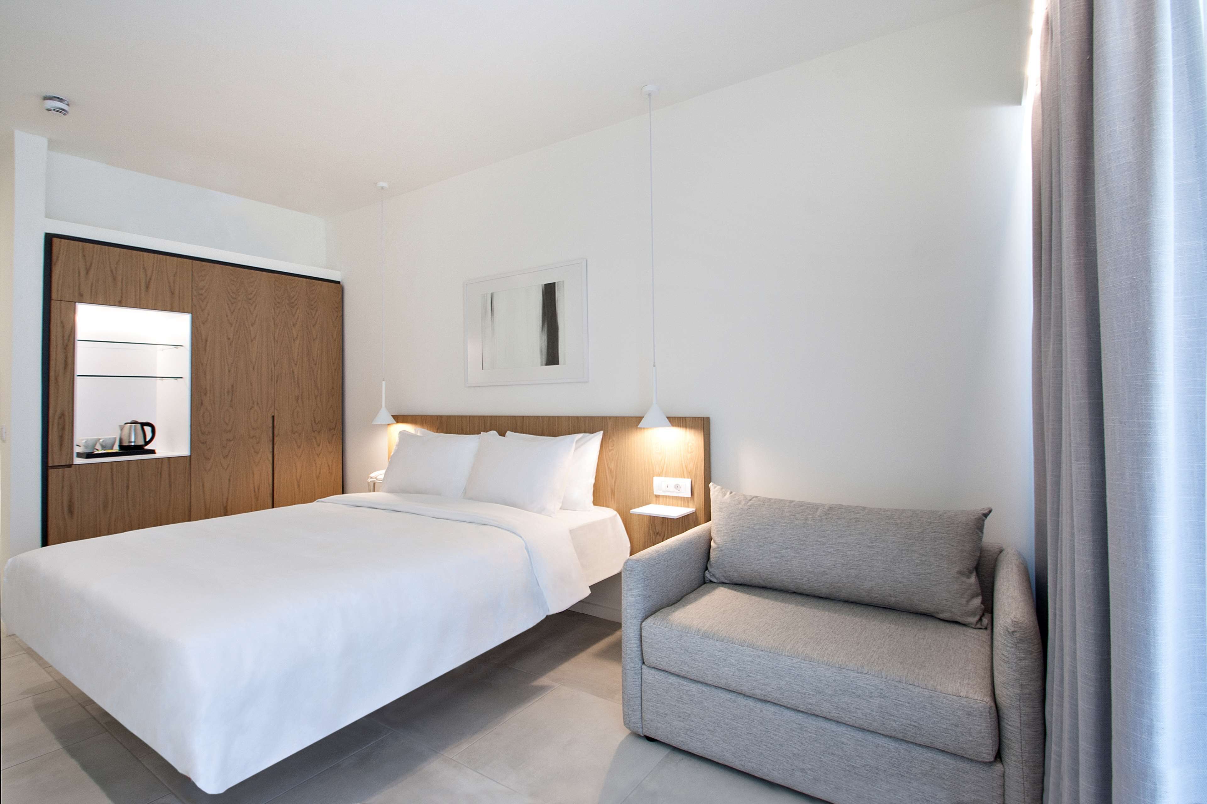 Ein Hotelzimmer mit einem großen Bett, einer Sitzecke, einem Nachttisch mit Lampe und einem Kleiderschrank.