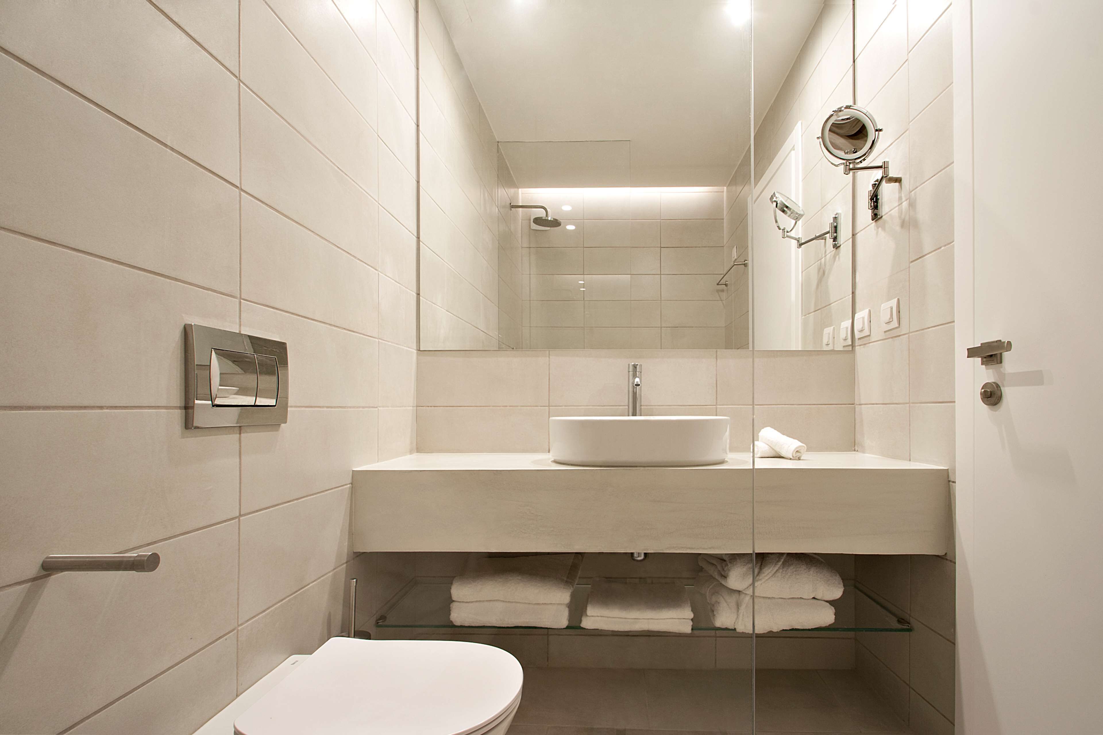 A modern bathroom with a white sink, mirror, and toilet.