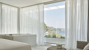 Quarto de hotel moderno com uma janela grande, banheira e sofá.