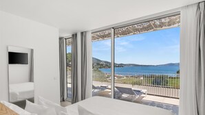 Quarto de hotel com varanda, televisão e cama.