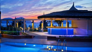 A poolside area with a bar and lounge chairs, overlooking a body of water and mountains. - Liberty Lykia  - Adults Only (Fethiye)