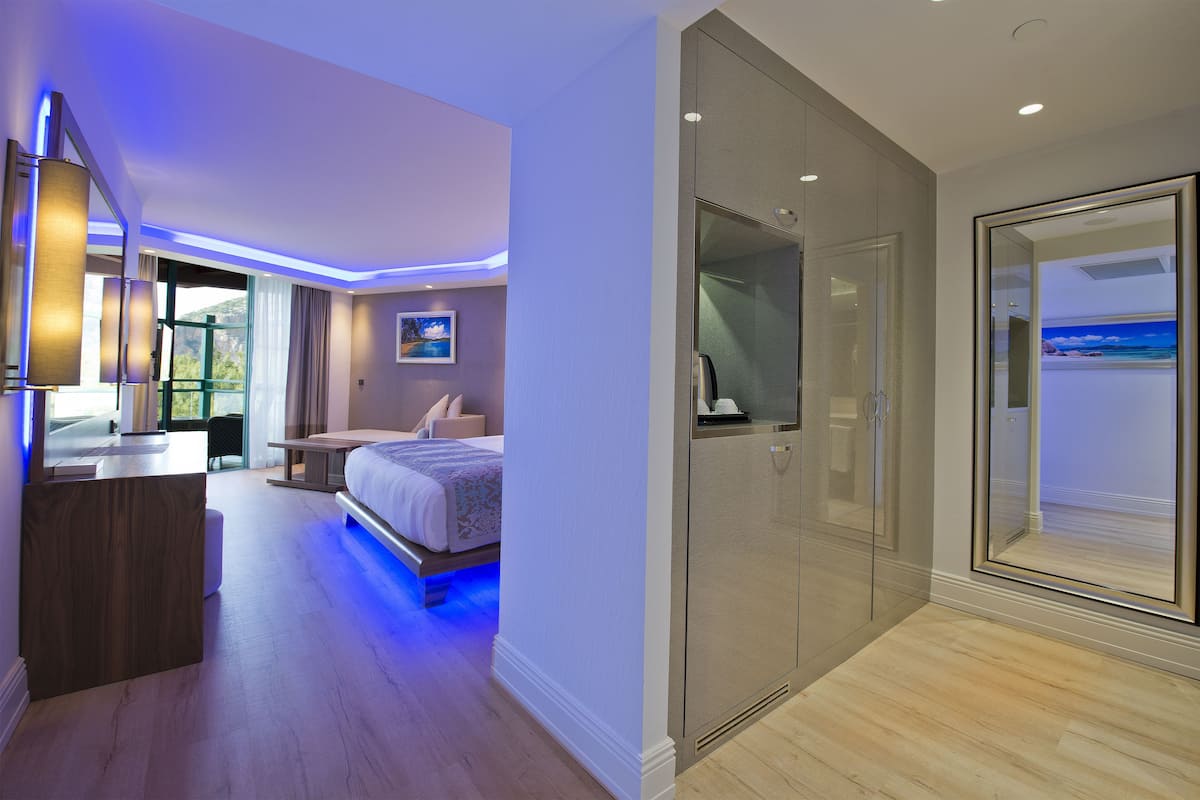 A modern hotel room with a bed, bedside table, and a large window.