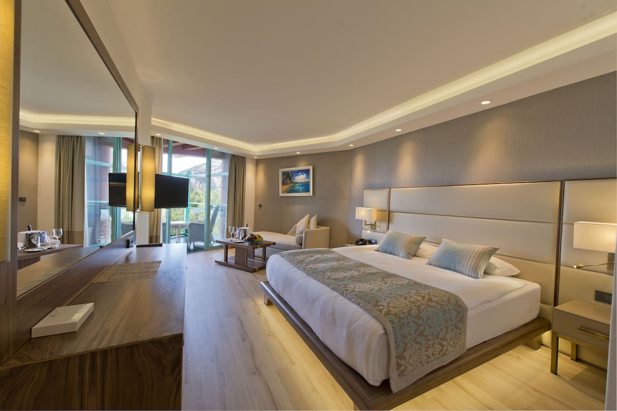 A modern hotel room with a large bed, a desk, a chair, and a TV.