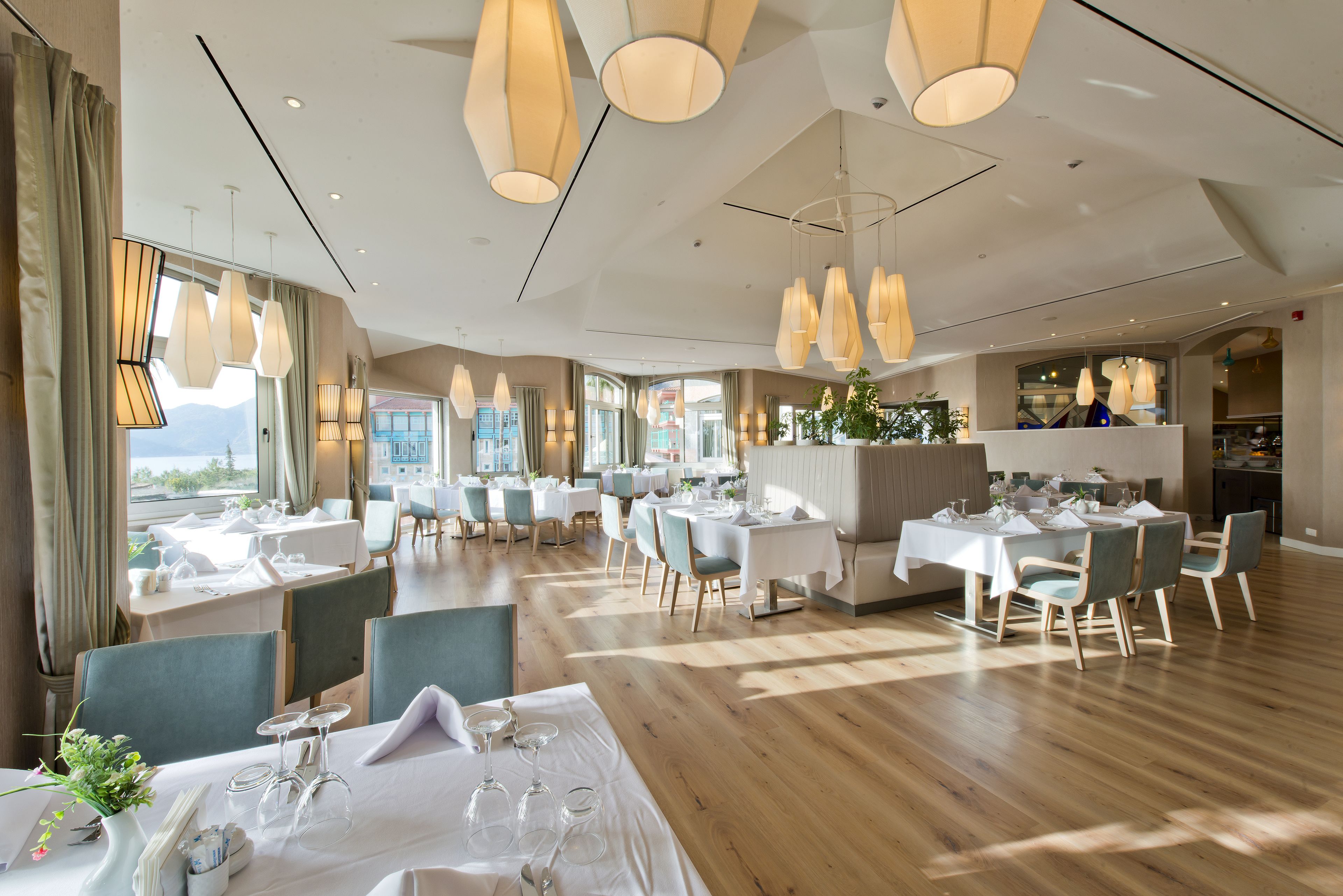 A restaurant with multiple dining tables, chairs, and hanging pendant lights.