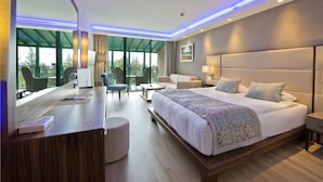 A modern hotel room with a large bed, a desk, and a balcony with outdoor seating. - Liberty Lykia  - Adults Only (Fethiye)