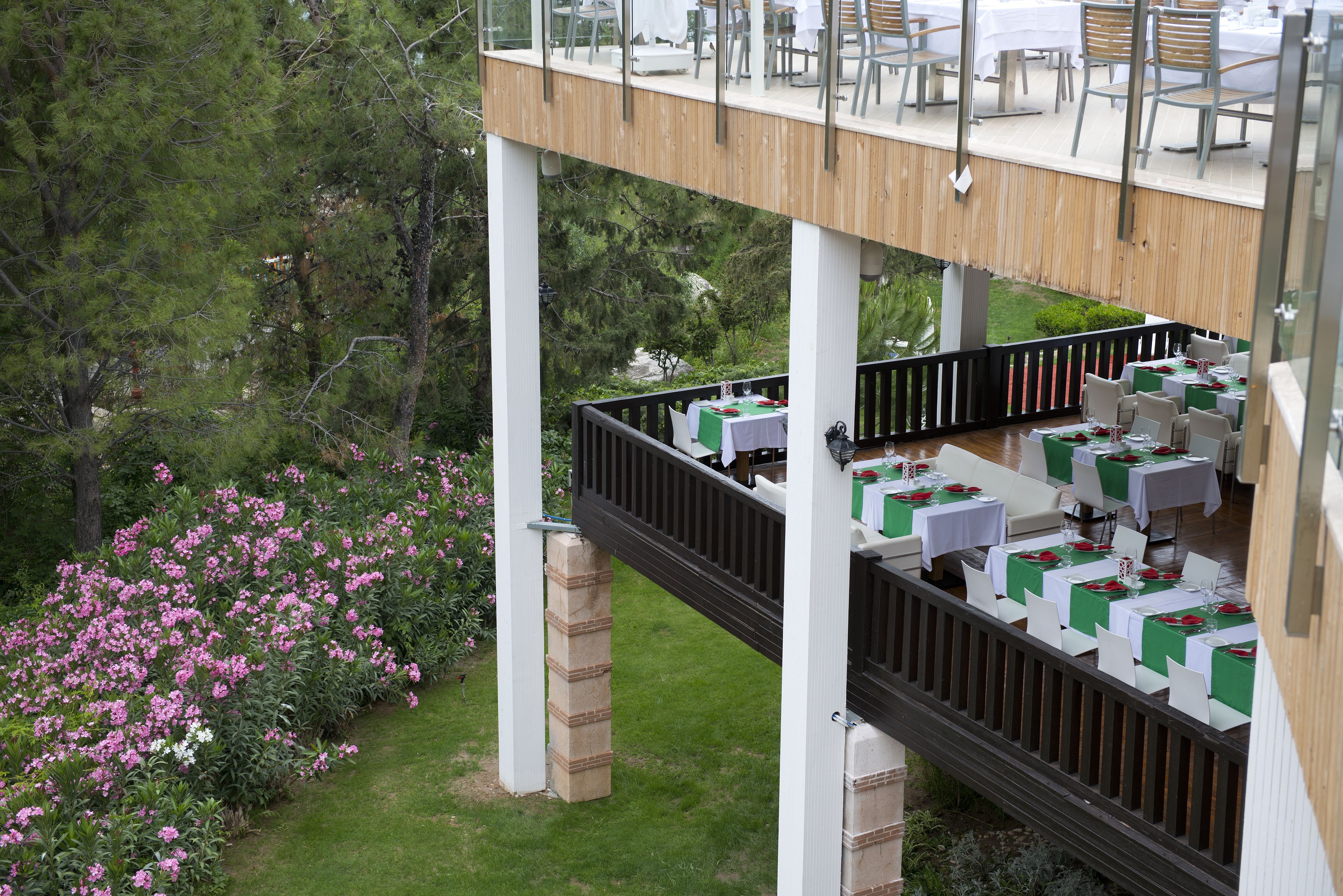Un área de comedor al aire libre con mesas y sillas, rodeada de exuberante follaje y plantas en flor.