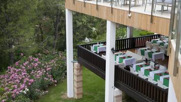 Un área de comedor al aire libre con mesas y sillas, rodeada de exuberante follaje y plantas en flor.