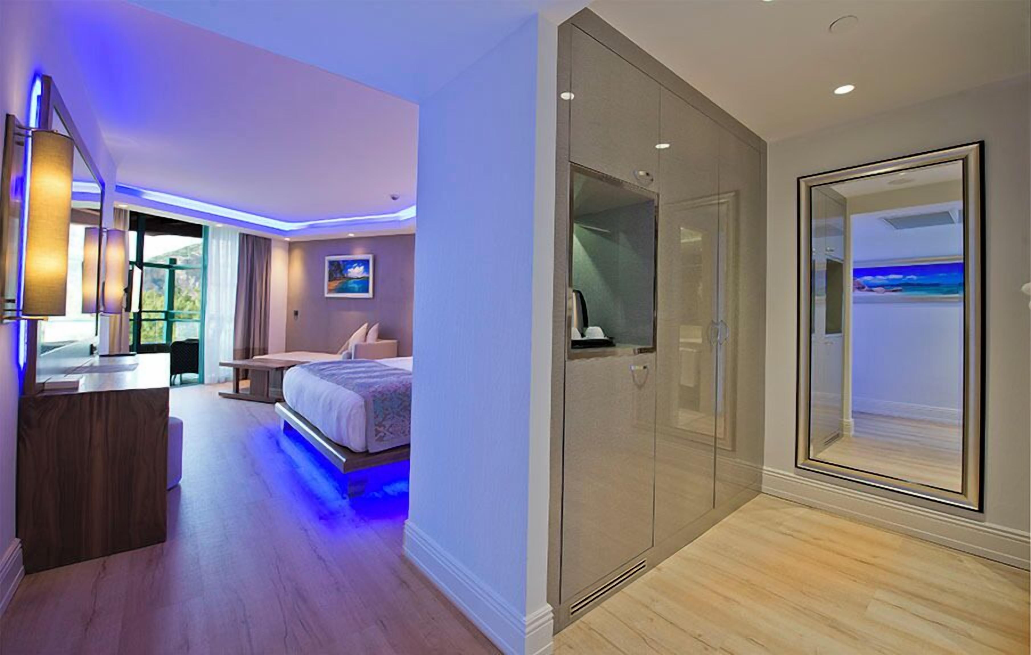 A modern hotel room with a bed, bedside table, and a large window.