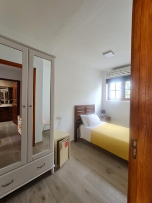 A bedroom with a bed, a wardrobe, a nightstand, and a window. - Casas DEL SOL Bungalows (Yaiza)