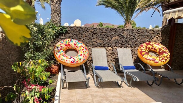 Zona de piscina con sillones de descanso y dos flotadores grandes con forma de dona.
