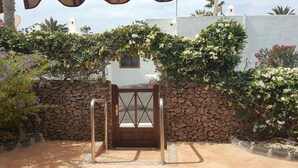 Una entrada protegida con un muro de piedra y abundante vegetación.