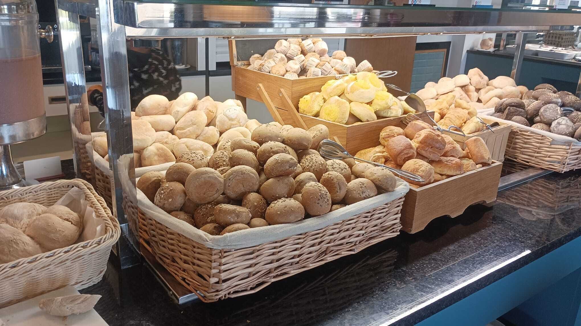 A buffet with various breads and pastries displayed in wicker baskets.