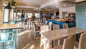 A restaurant with multiple dining areas, including a bar and a counter with food items. - Ukino Terrace Algarve - Concept Hotel (Lagoa)