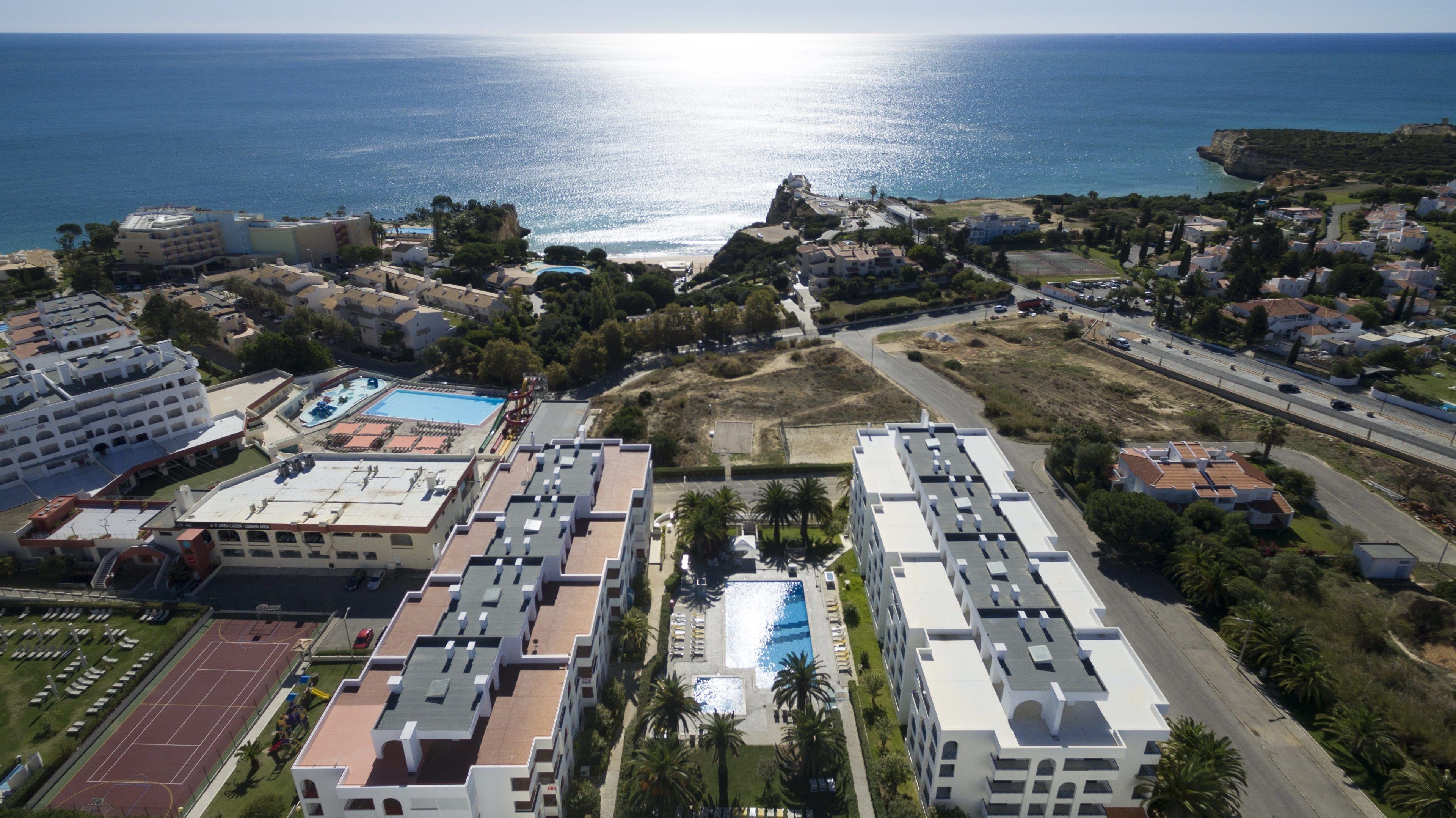 Un complexe hôtelier comprenant plusieurs bâtiments, une piscine et offrant une vue sur la mer.