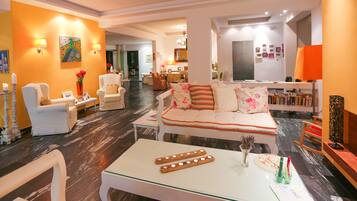 A modern living room with a sofa, chairs, a coffee table, and a dining area in the background.