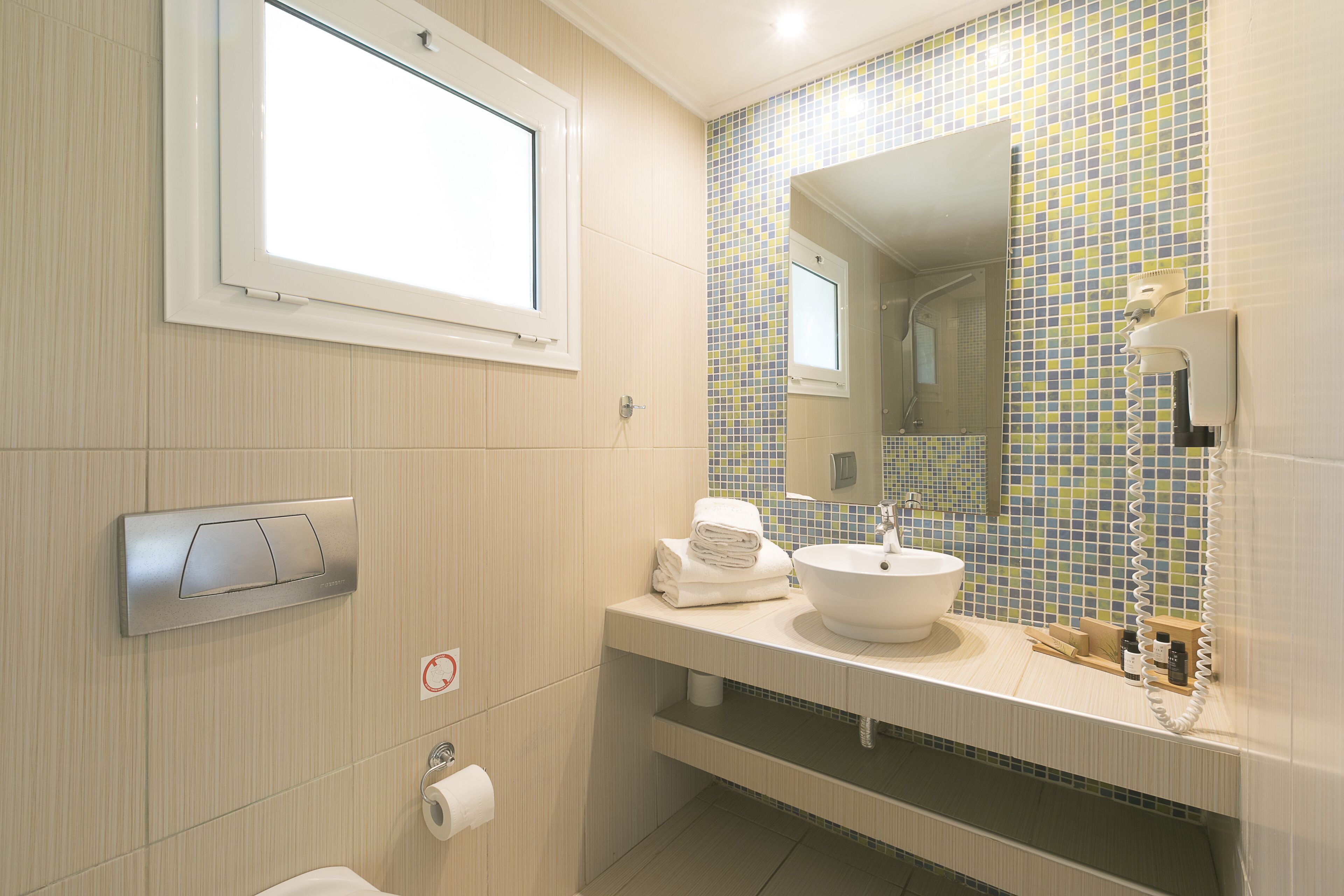 A modern bathroom with a window, a sink, a mirror, and a towel rack.