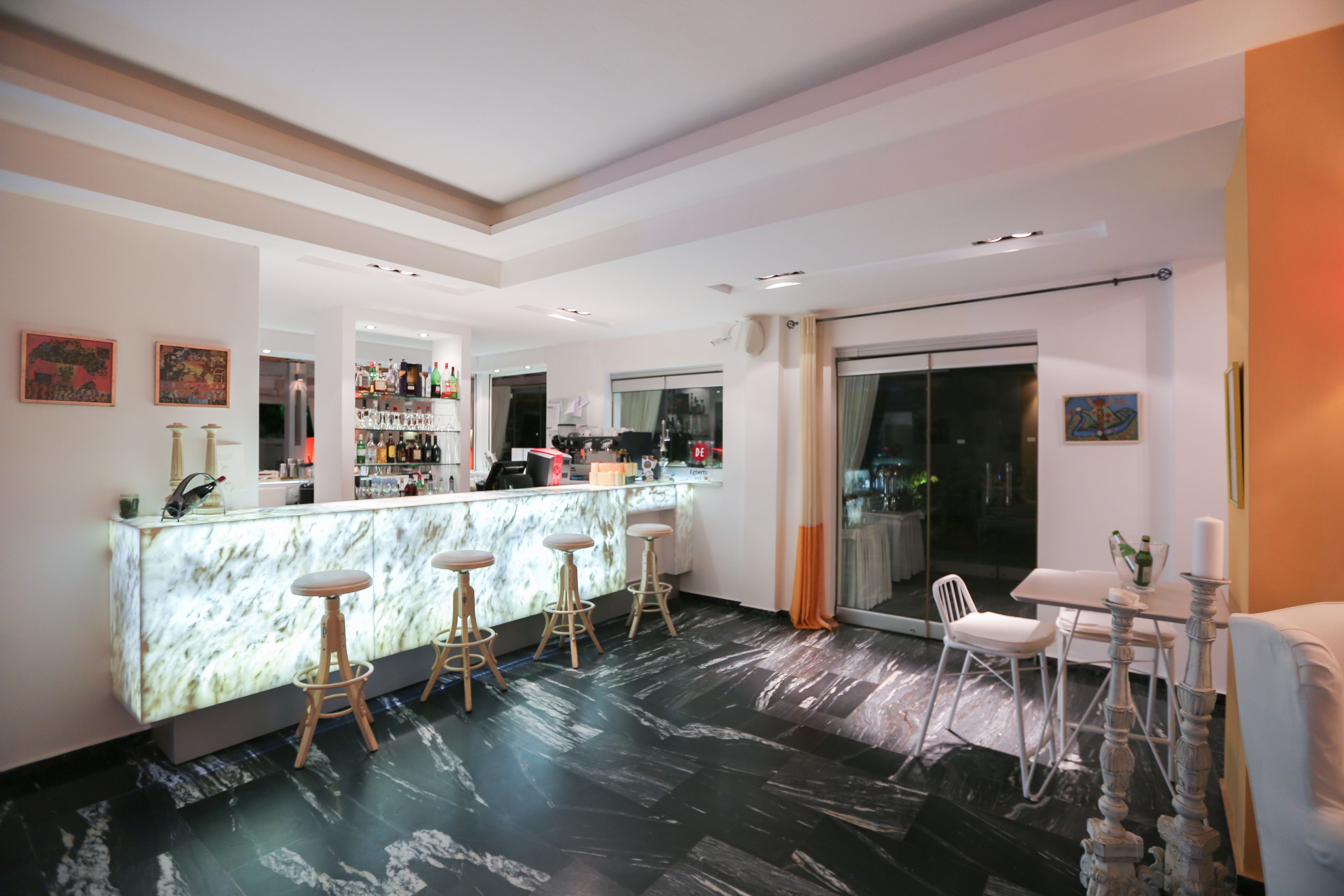 A modern bar area with a marble countertop, bar stools, and a seating area with a table and chairs.