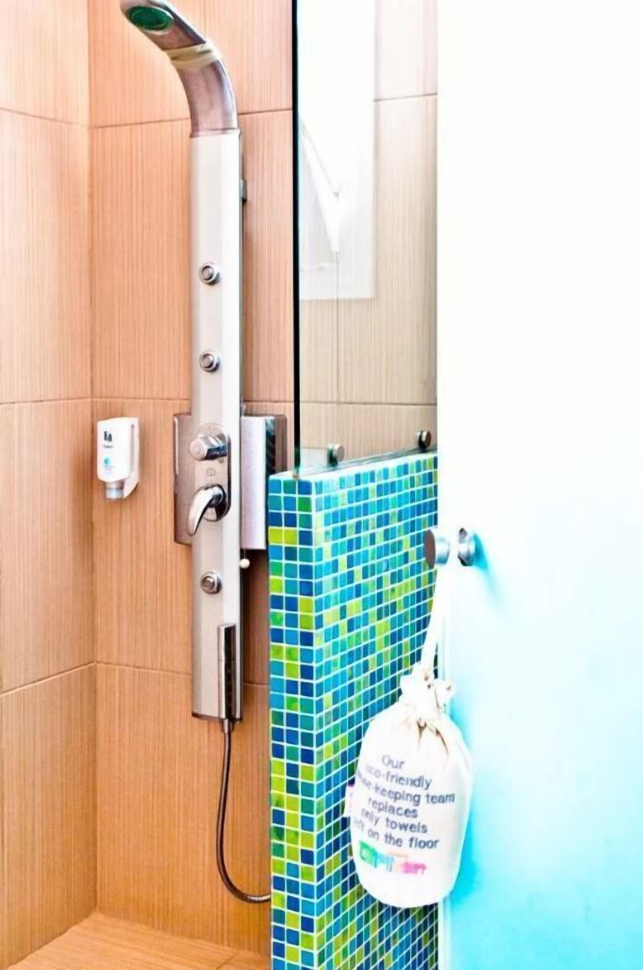 A shower with a modern design, a towel rack, and a sign about eco-friendly practices.
