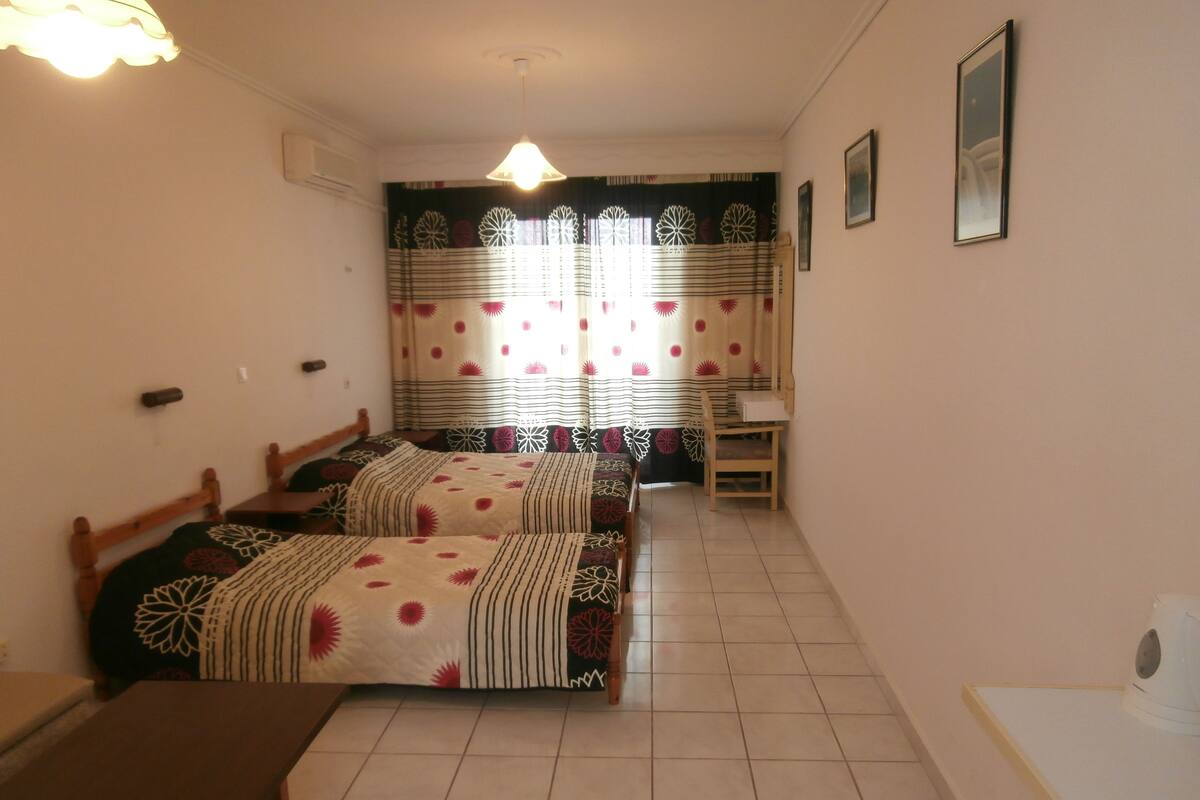 A room with two beds, a small table, a chair, and a desk.