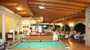 An indoor recreational area with a pool table, seating, and a stone archway. - Panorama Studios (Rhodes)