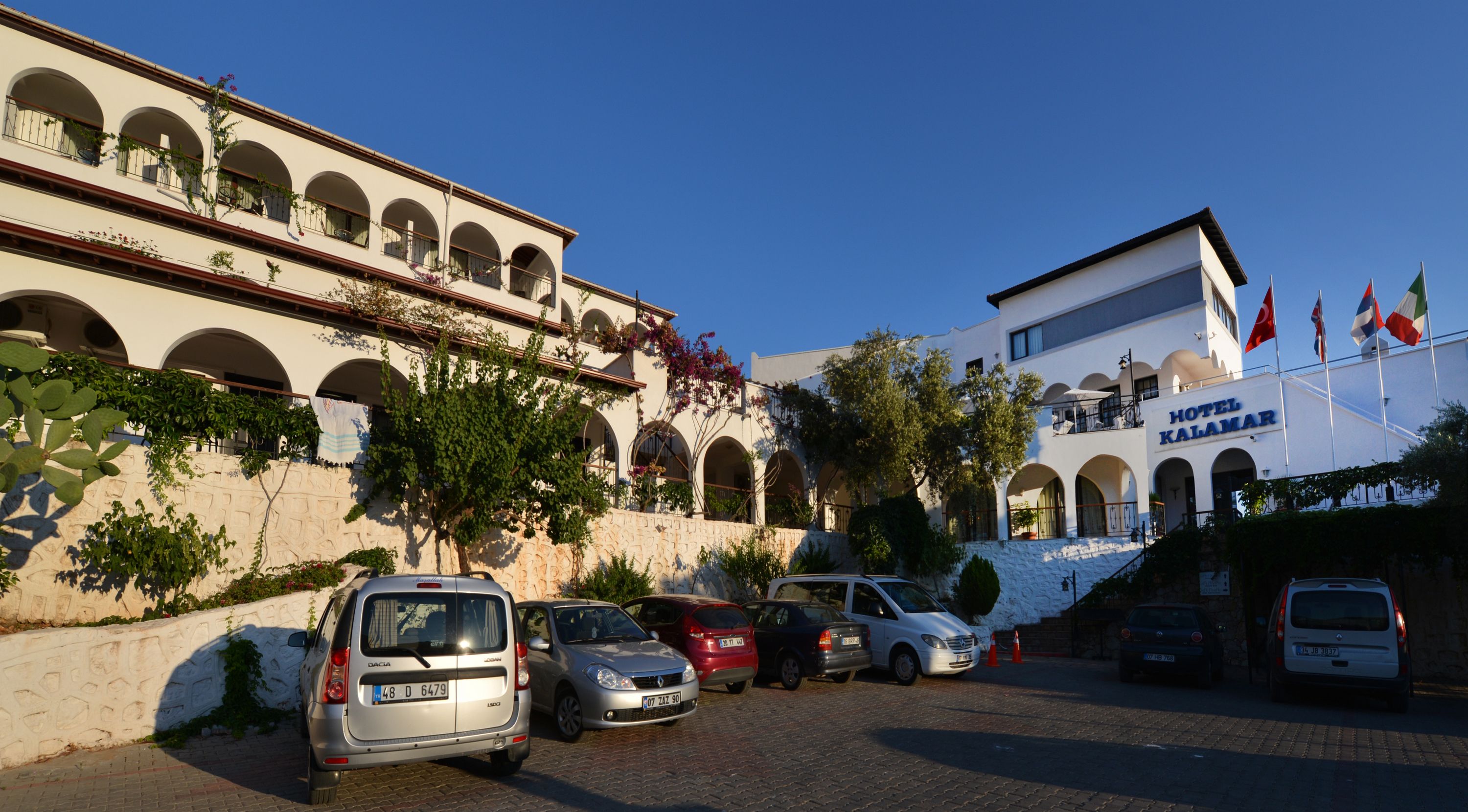 Ein Hotel mit steinernen Fassade, mehreren Bögen und Flaggen.