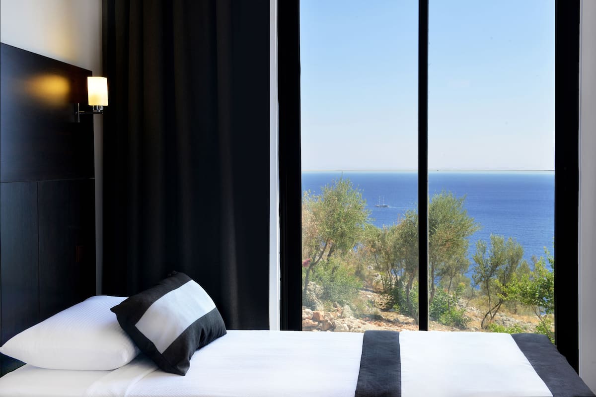 A bedroom with a large window overlooking a coastal landscape.
