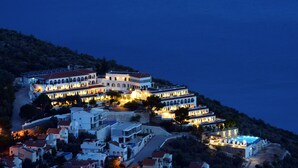 A coastal hotel with multiple buildings, a winding road, and a view of the sea. - Kalamar Hotel (Kas)