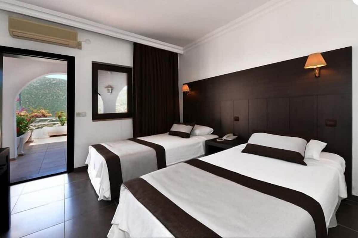 A hotel room with two beds, a large window, a mirror, and a door leading to an outdoor area.