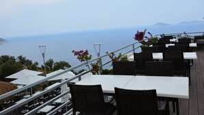 An outdoor dining area with tables and chairs, overlooking the sea. - Kalamar Hotel (Kas)