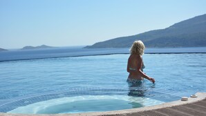 A person in a swimming pool with a view of the sea and hills. - Kalamar Hotel (Kas)