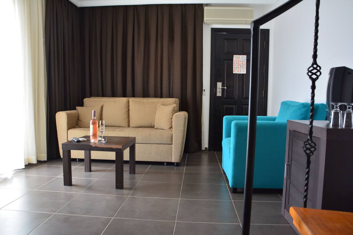 A living room with a beige sofa, a blue sofa, a coffee table, and a TV stand.