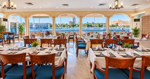 A restaurant with tables set for dining, a view of the water, and a mountainous landscape in the background. - Obelisk Nile Hotel Aswan (Aswan)