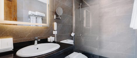 Un baño moderno con lavamanos, inodoro y zona de ducha.