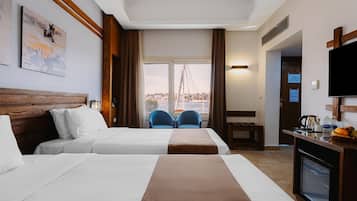 Habitación de hotel con dos camas, un televisor, un escritorio con cafetera y vistas a un puente.