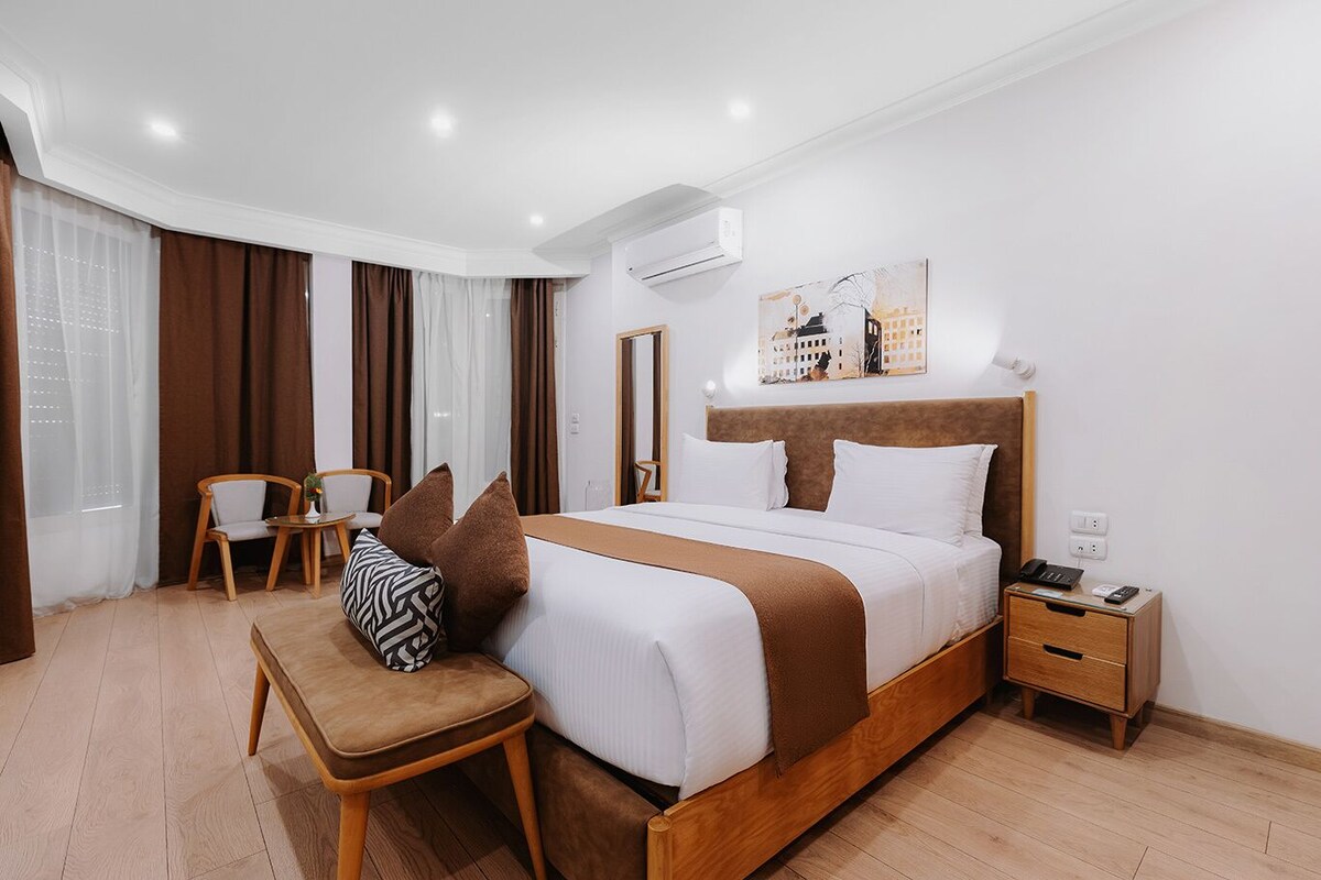 Una habitación de hotel con cama, mesita de noche, silla y equipo de aire acondicionado.