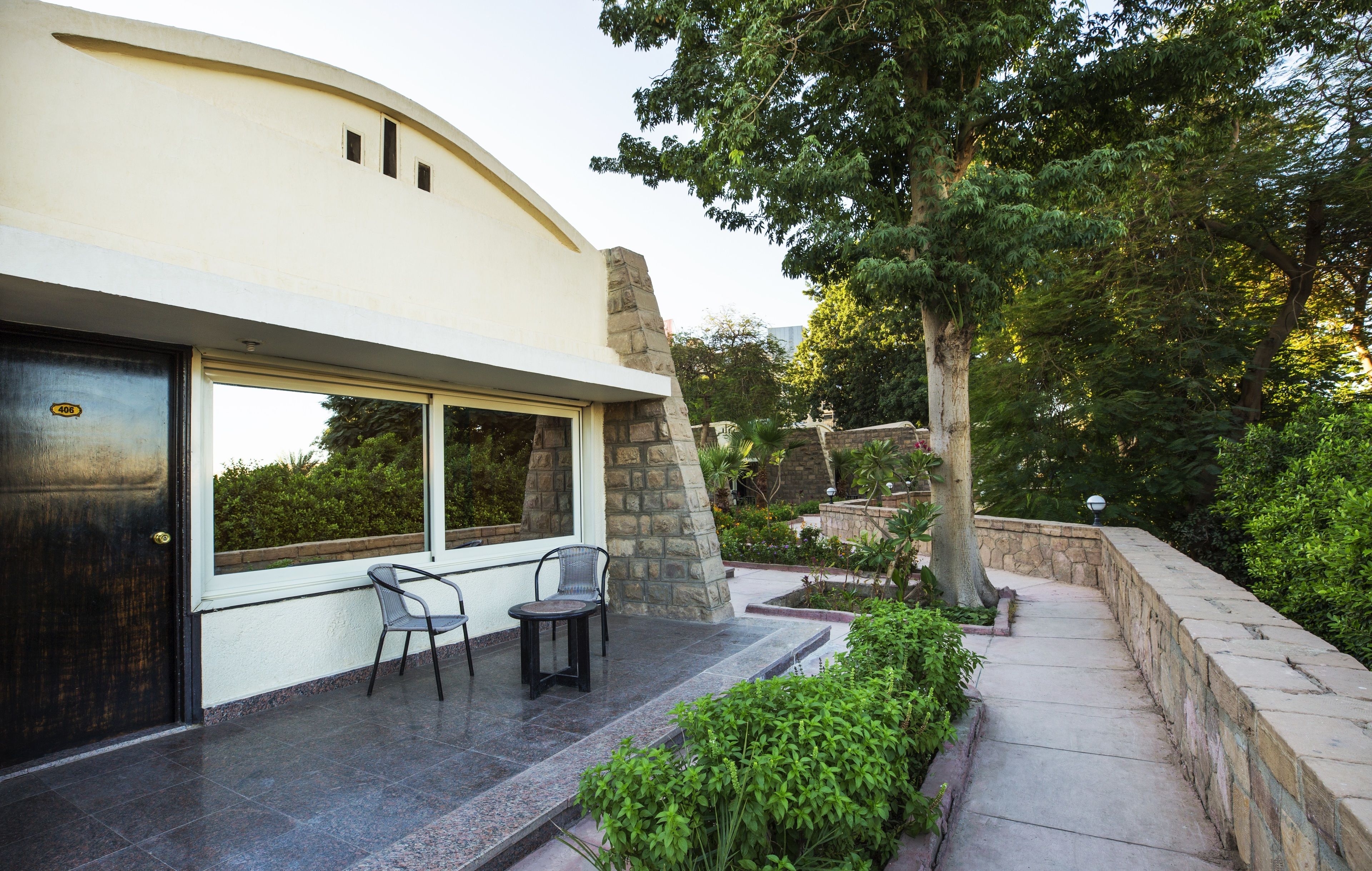 Ein modernes Haus mit Terrasse, Steinmauern und einem großen Fenster mit Blick auf einen Garten.