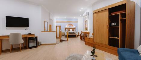 A modern living room with a TV, desk, chair, sofa, and a large wooden wardrobe.
