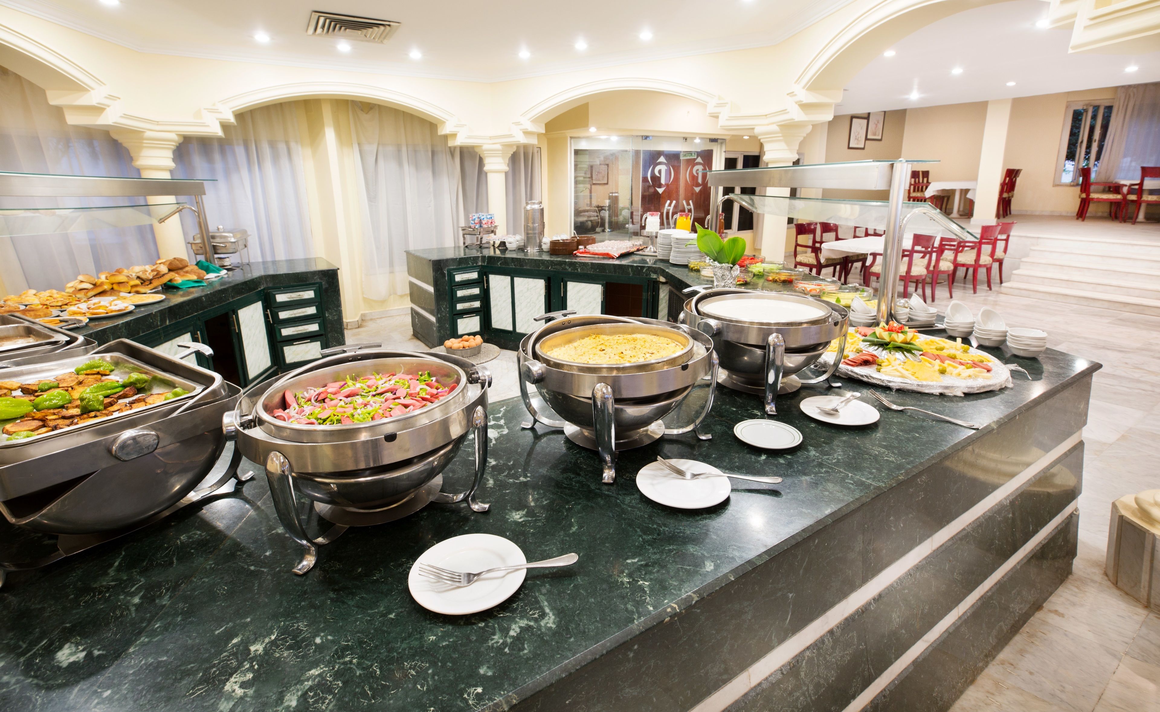 Una mesa de buffet con diversos alimentos y utensilios para servir.