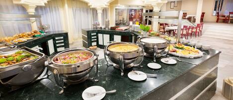 Una mesa de buffet con diversos alimentos y utensilios para servir.