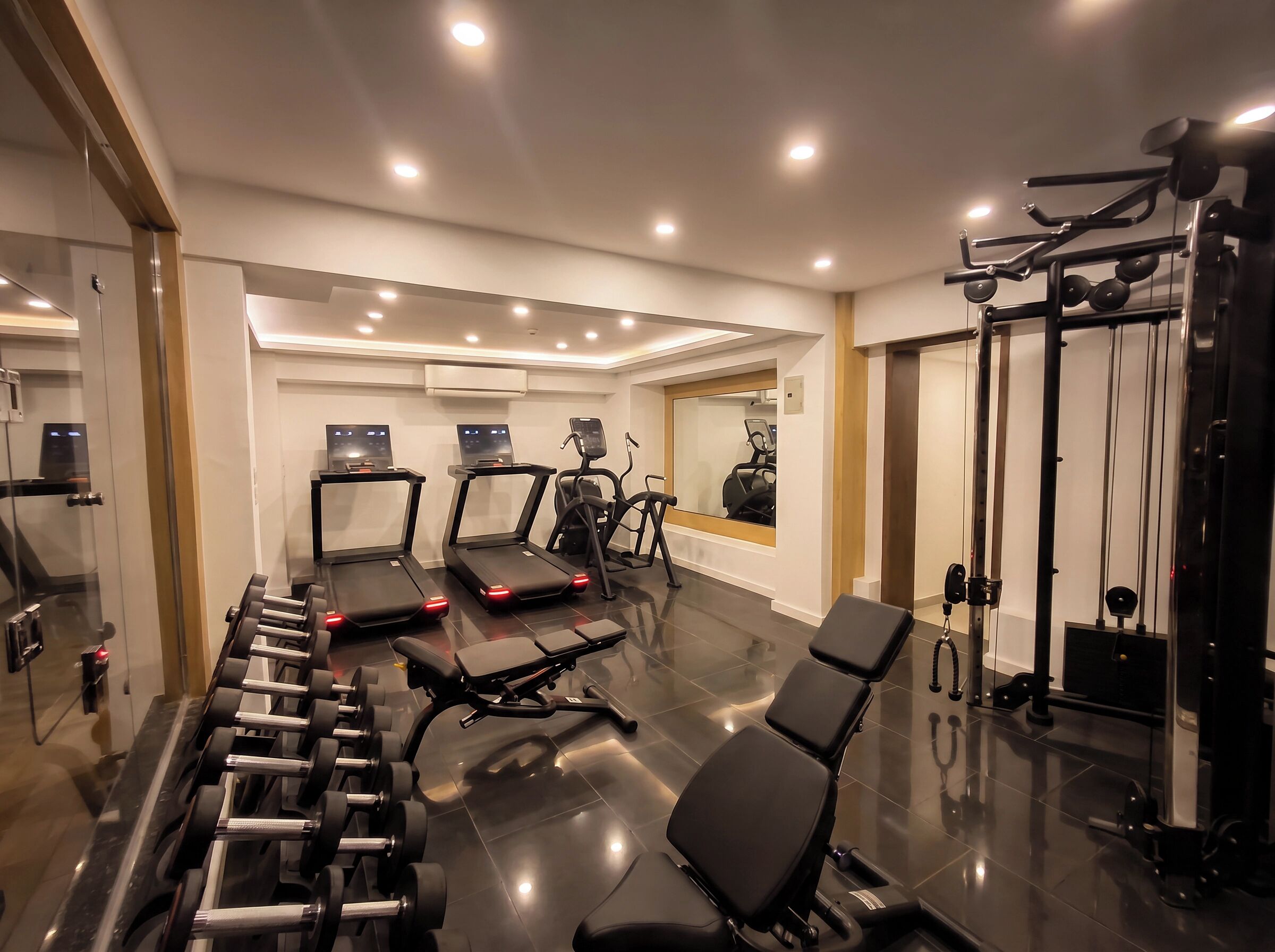 A modern gym with treadmills, weight benches, and a squat rack.