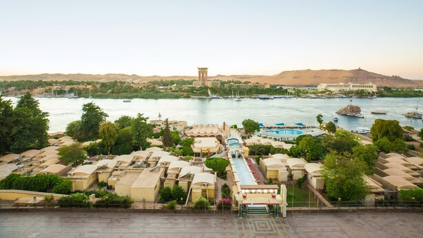 Un hotel costero con varias edificaciones, una piscina y barcos en el agua.