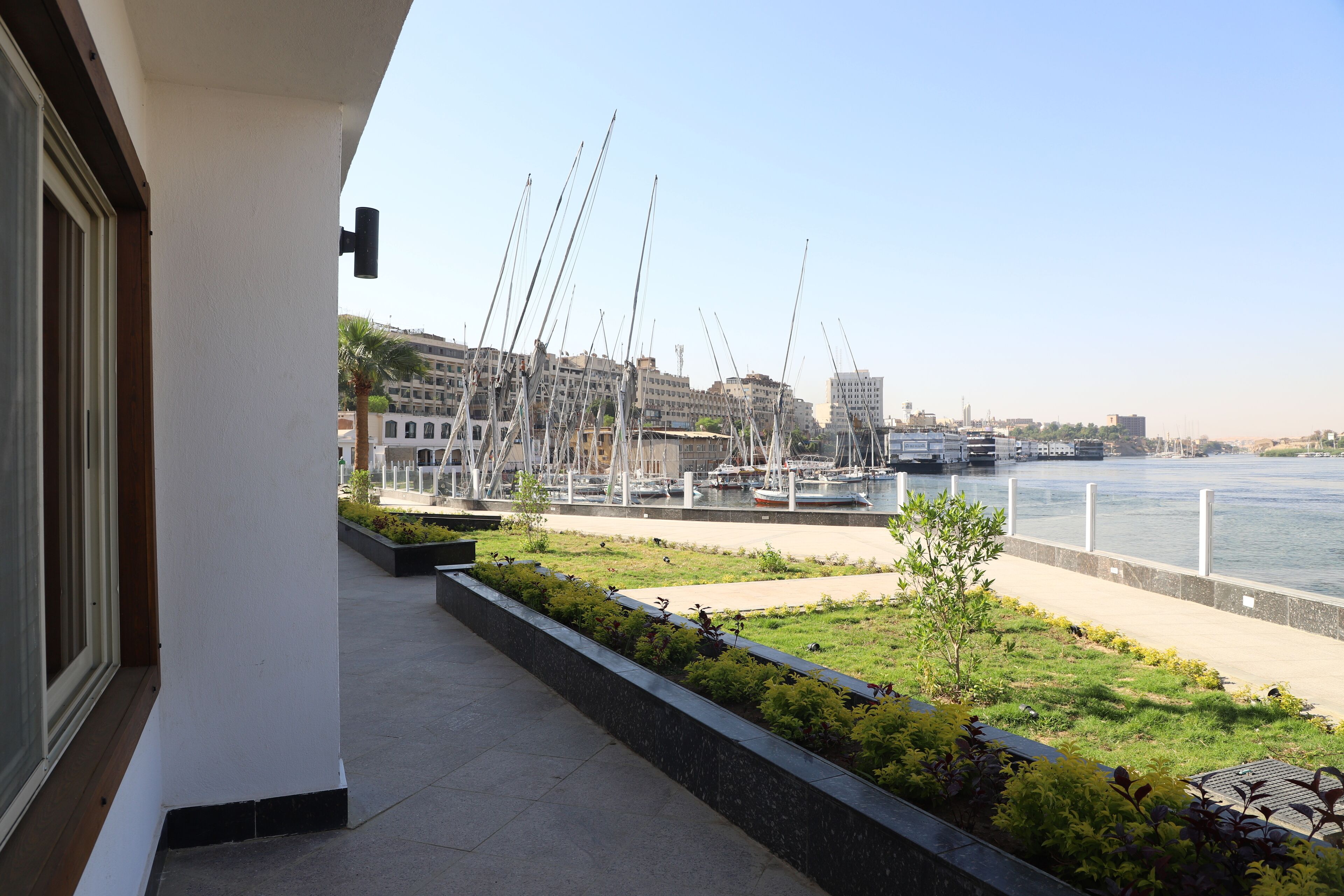 A balcony with a view of a marina, boats, and buildings across the water.