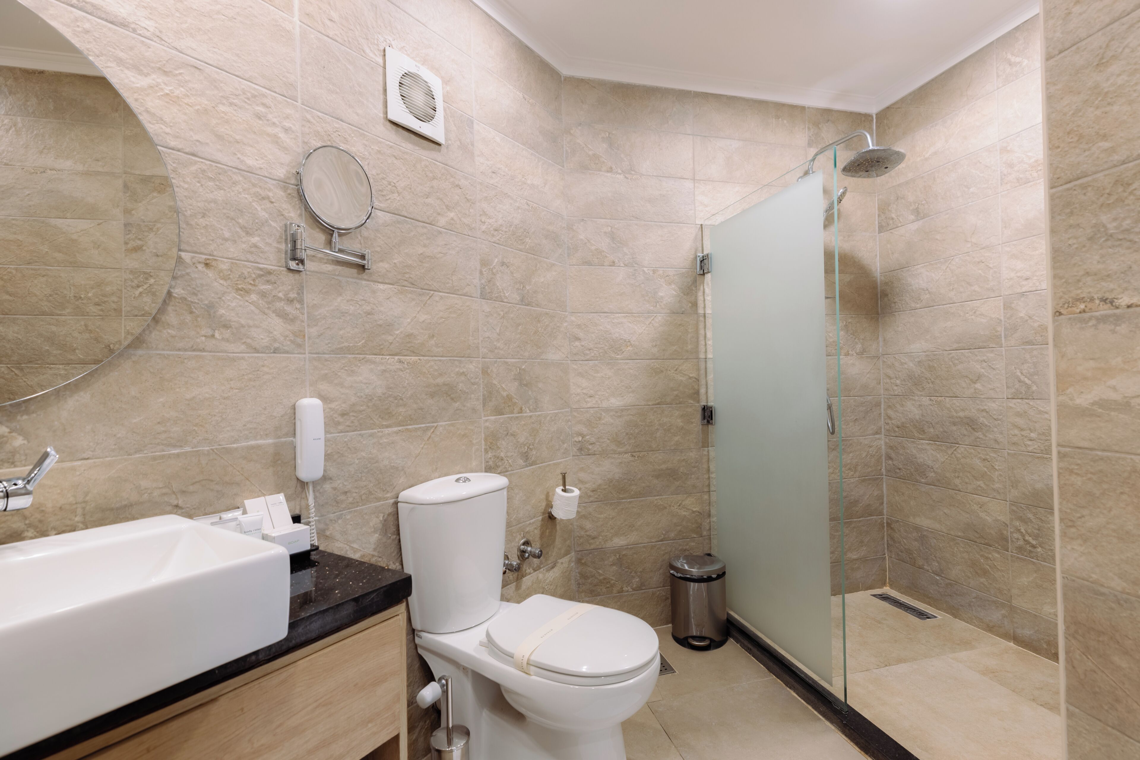 Une salle de bain avec un lavabo, des toilettes et une douche, le tout de couleur blanche.