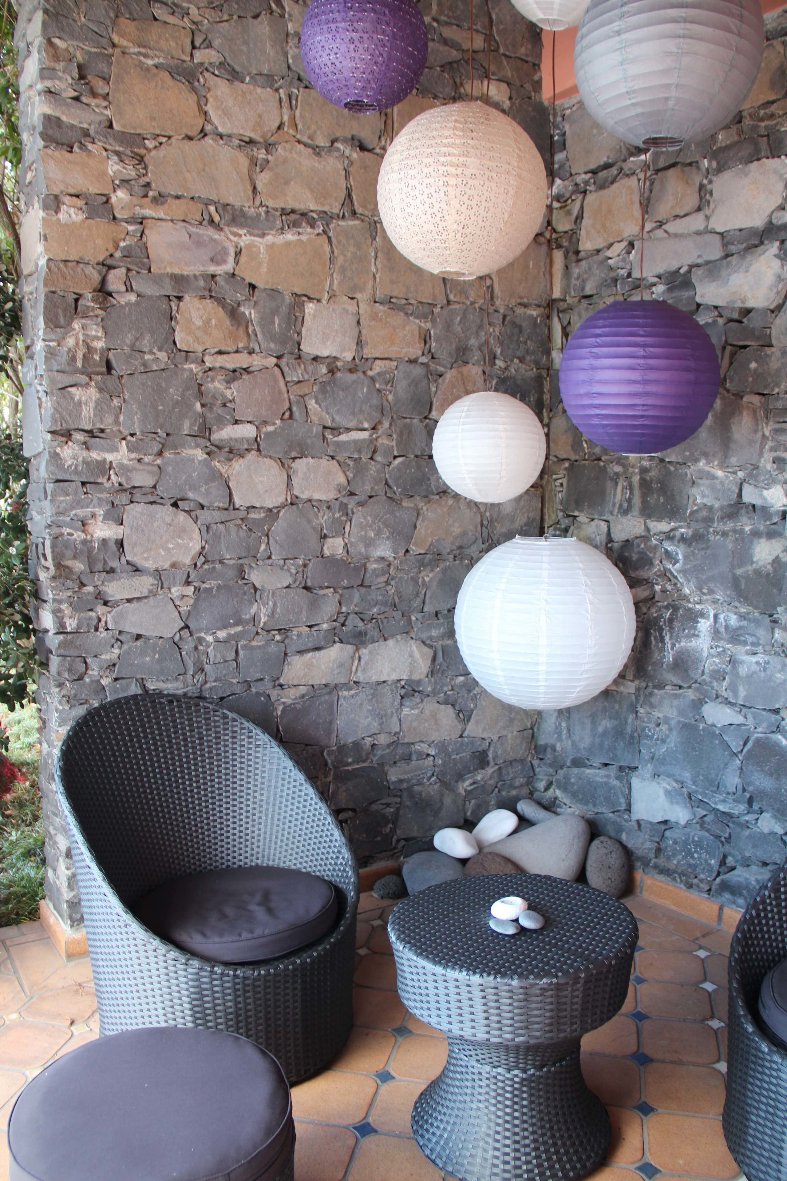 Wicker furniture, stone wall, and hanging paper lanterns.