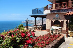 A restaurant with outdoor seating overlooking the sea. - Hotel Ocean Gardens (Funchal)