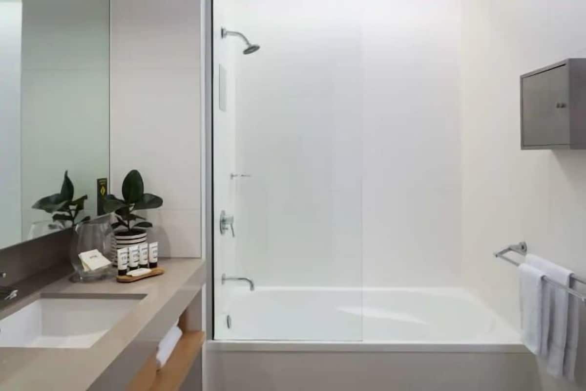 Un baño moderno con cabina de ducha de vidrio, un espejo grande y un lavamanos con encimera.
