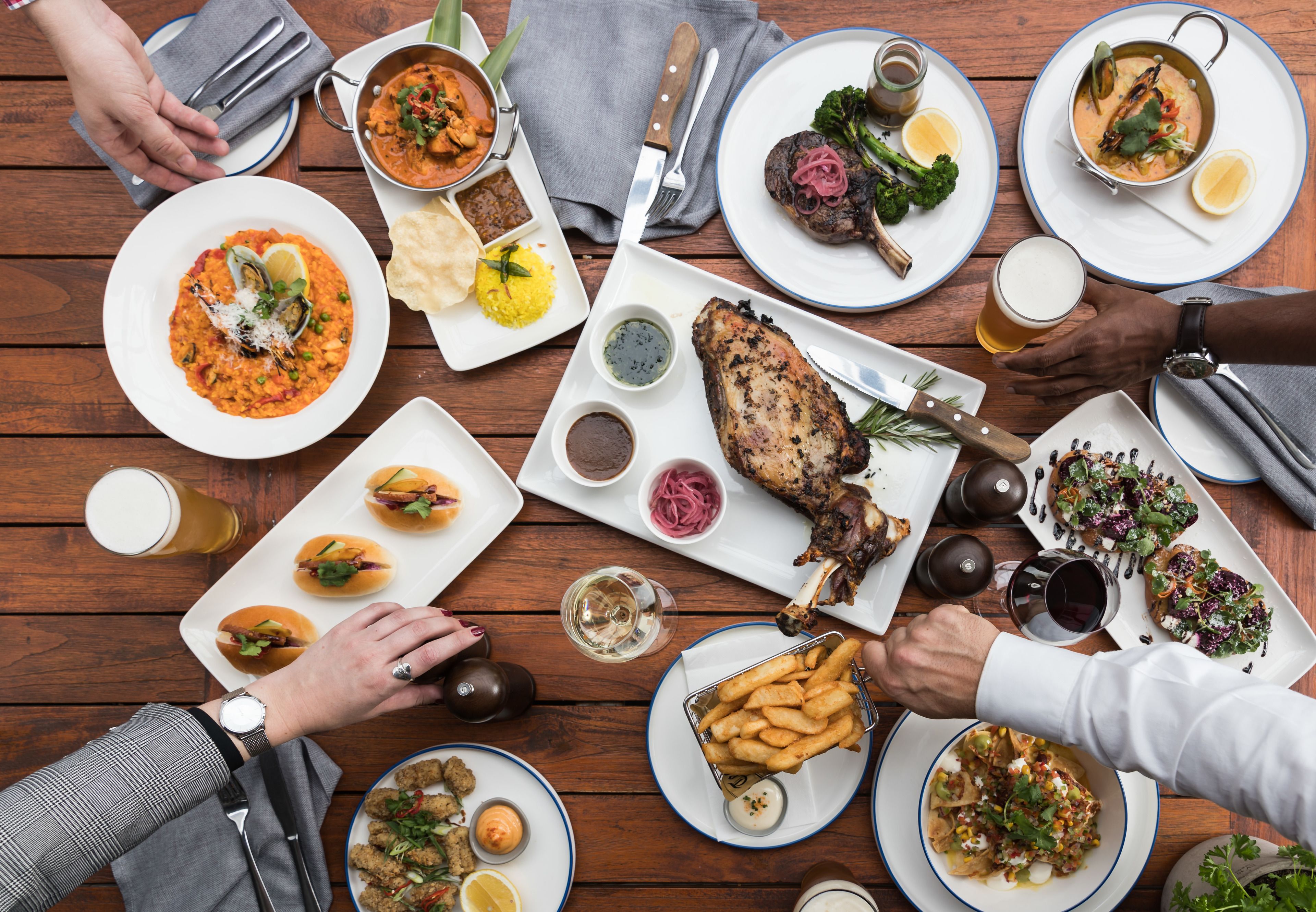 A dining table with various dishes, including seafood, meat, and sides, along with drinks and utensils.