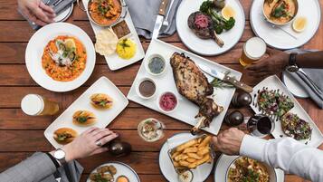 A dining table with various dishes, including seafood, meat, and sides, along with drinks and utensils.