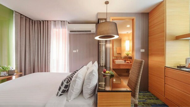 Een hotelkamer met een bed, een bureau, een stoel, een spiegel, een wastafel en een douche.